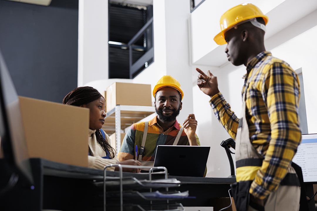 Membres de l'équipe Optima Solution en casque de chantier échangeant autour d'un ordinateur